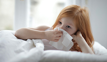 The images shows a kid who is blowing her nose