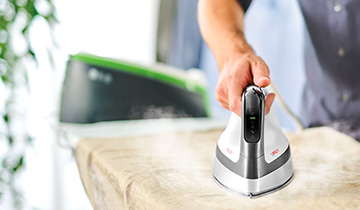 The image shows a man who is ironing a linen shirt